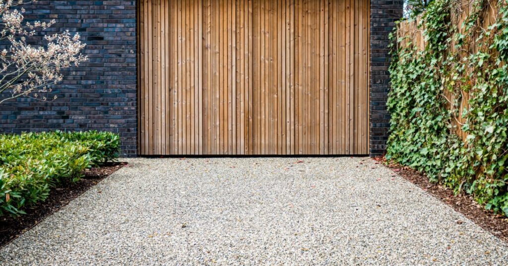 porte de garage en bois avec une allée en gravier