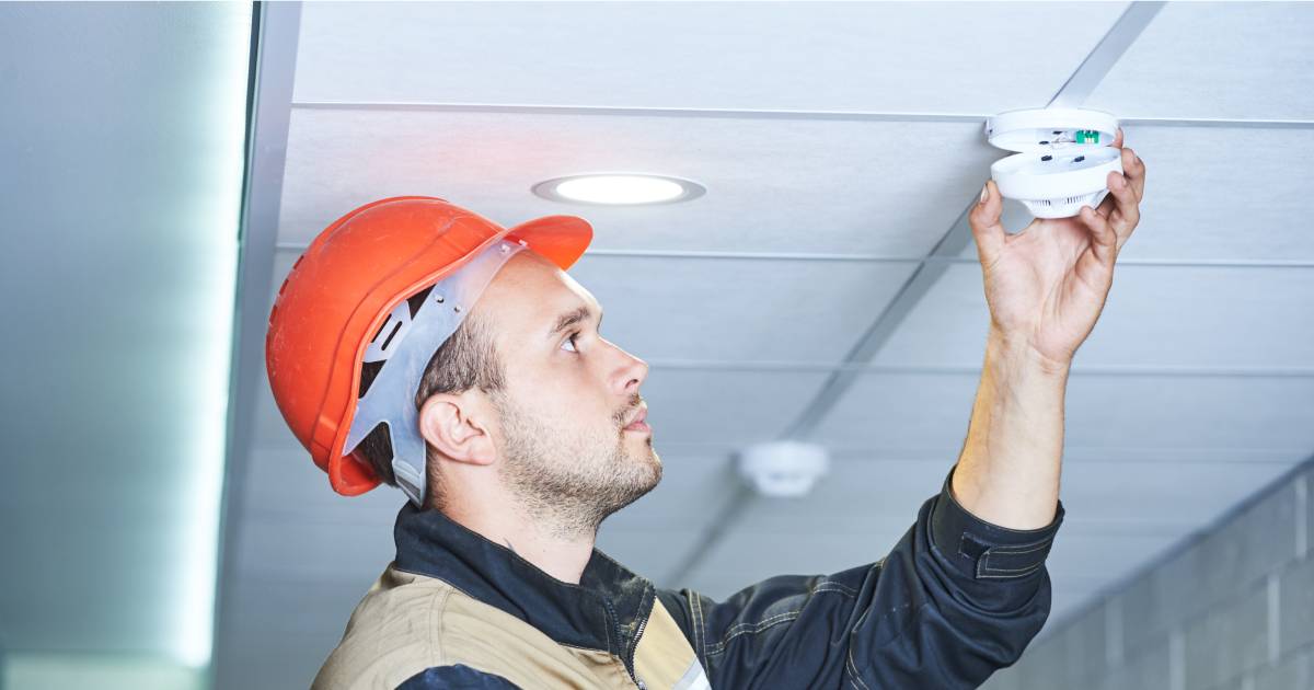 un homme installant un détecteur de fumée