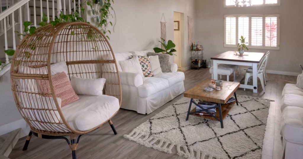salon moderne dans un style épuré avec un tapis blanc et noir au sol avec motif berbere, des plantes vertes, un table basse en bois brut et des fauteuils blancs