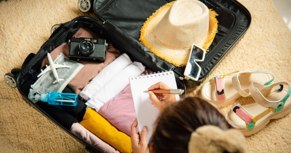 personne en train de vérifier sa liste des essentiels à prendre dans sa valise avant son dpart en vacances