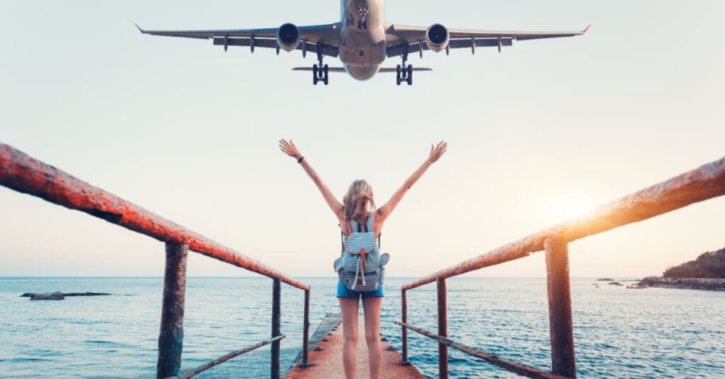 femme bras levé devant avion