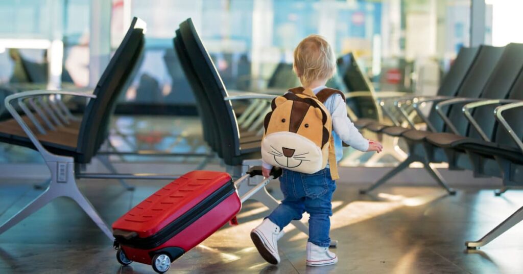 Enfant avec sac à dos et valise dans un aéroport