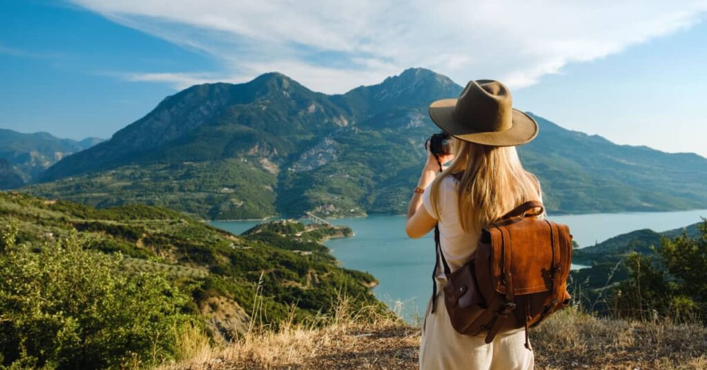 femme en train de photographier une montagne en face d'elle à l'aide d'un appareil réflex