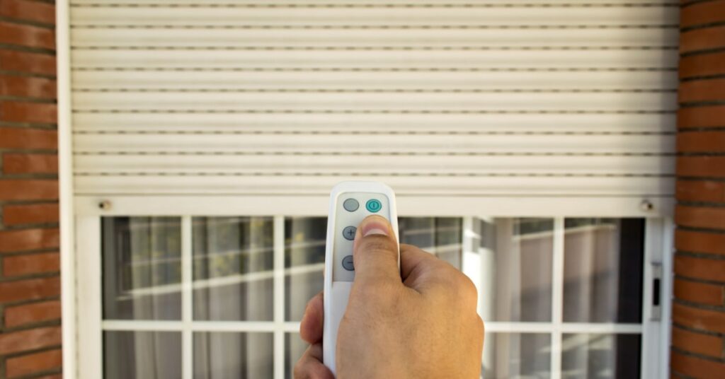 personne en train de descendre son volet roulant avec une télécommande sans fil pour descendre le volet d'une maison